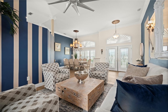 living room with french doors, ceiling fan with notable chandelier, crown molding, and hardwood / wood-style floors