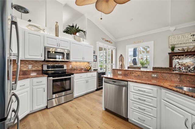 kitchen with appliances with stainless steel finishes, lofted ceiling, beverage cooler, and white cabinets