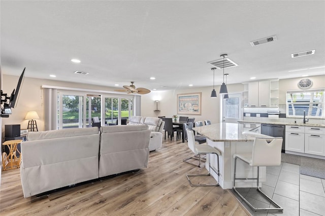 living room with ceiling fan, light hardwood / wood-style floors, and sink