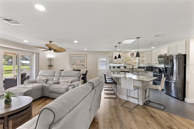 living room with light hardwood / wood-style floors and ceiling fan