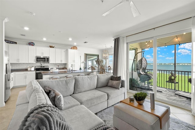 tiled living room with crown molding and a water view