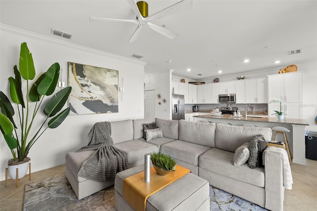 living room with ceiling fan, ornamental molding, and light tile patterned floors