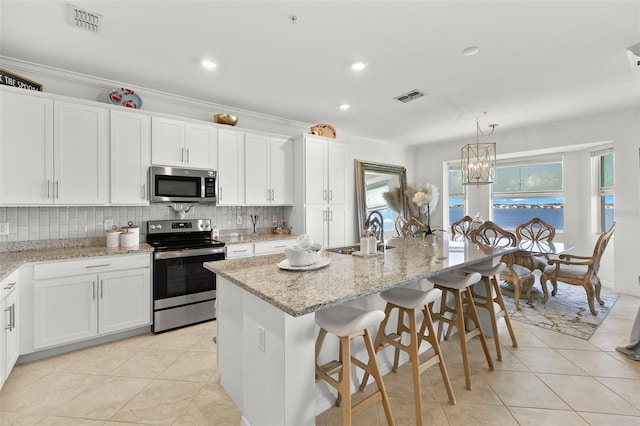 kitchen featuring a center island with sink, appliances with stainless steel finishes, white cabinetry, crown molding, and sink