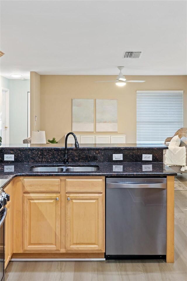 kitchen featuring dark stone countertops, sink, stainless steel dishwasher, and light hardwood / wood-style flooring