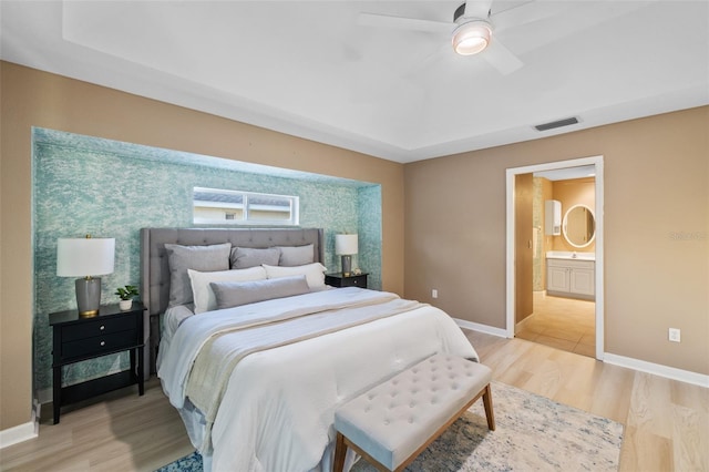 bedroom featuring ceiling fan, light wood-type flooring, and connected bathroom