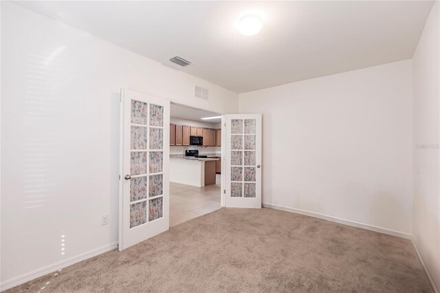 empty room featuring french doors and light carpet