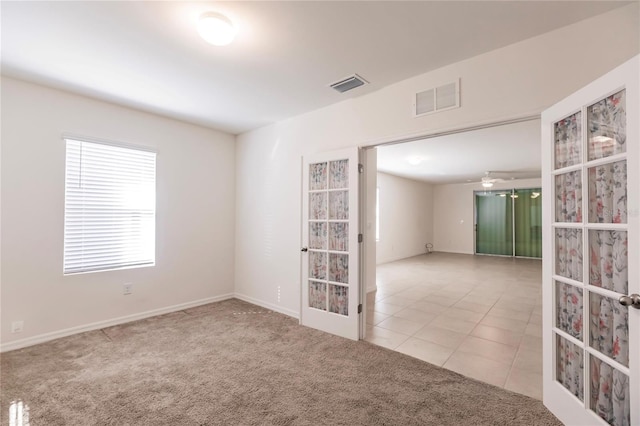 empty room featuring french doors, light colored carpet, and ceiling fan