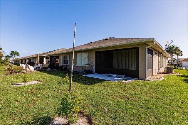 back of property featuring central AC and a lawn