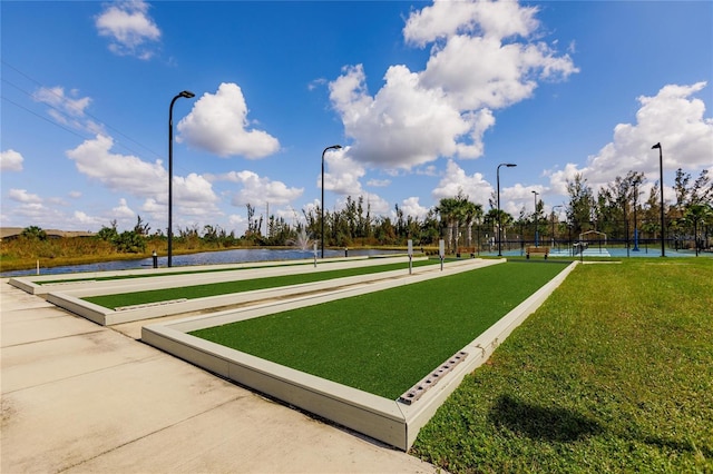 view of property's community with a water view, a lawn, and tennis court