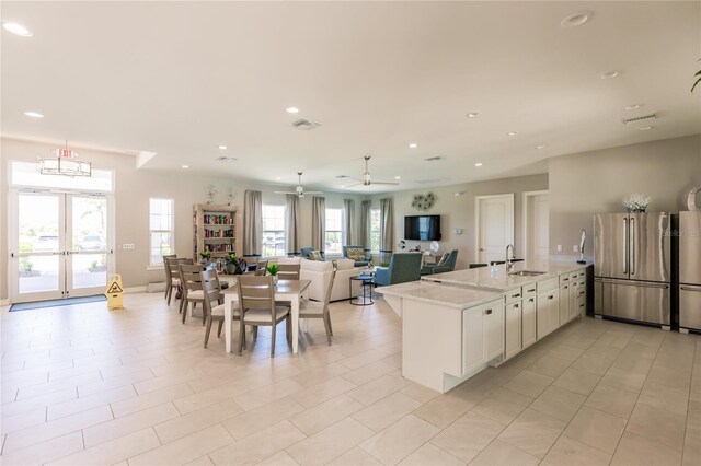 kitchen with sink, stainless steel fridge, light stone countertops, white cabinets, and ceiling fan