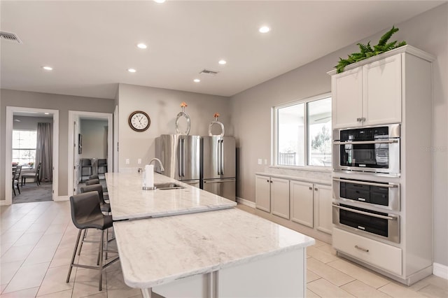 kitchen with white cabinetry, light stone counters, and plenty of natural light