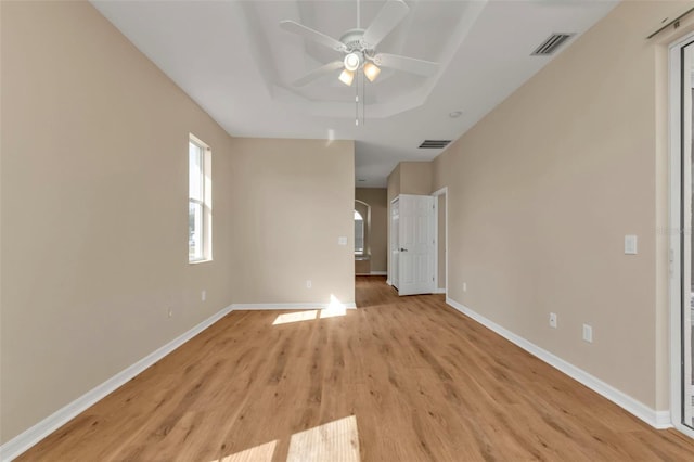 empty room featuring ceiling fan, a raised ceiling, and light hardwood / wood-style flooring