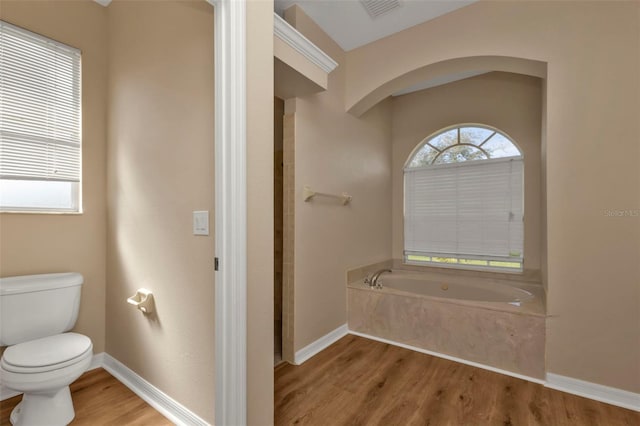 bathroom featuring a tub to relax in, toilet, and hardwood / wood-style flooring