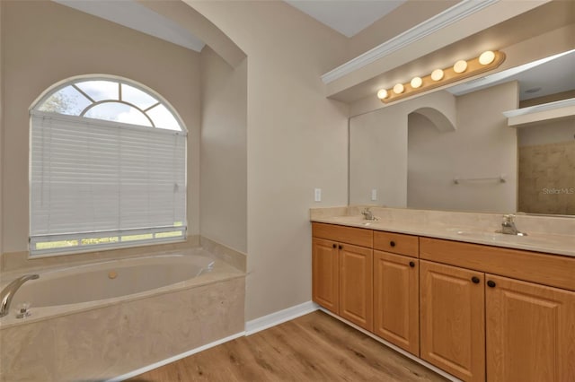 bathroom with hardwood / wood-style floors, a relaxing tiled tub, and vanity