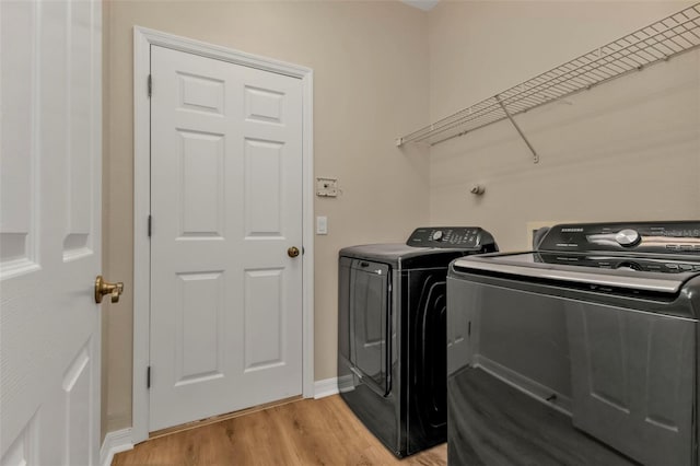 washroom with light hardwood / wood-style floors and washing machine and dryer