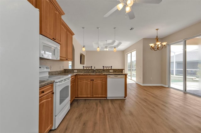 kitchen featuring kitchen peninsula, white appliances, ceiling fan with notable chandelier, decorative light fixtures, and light hardwood / wood-style floors