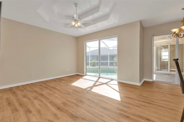 spare room featuring ceiling fan, light hardwood / wood-style floors, and a tray ceiling