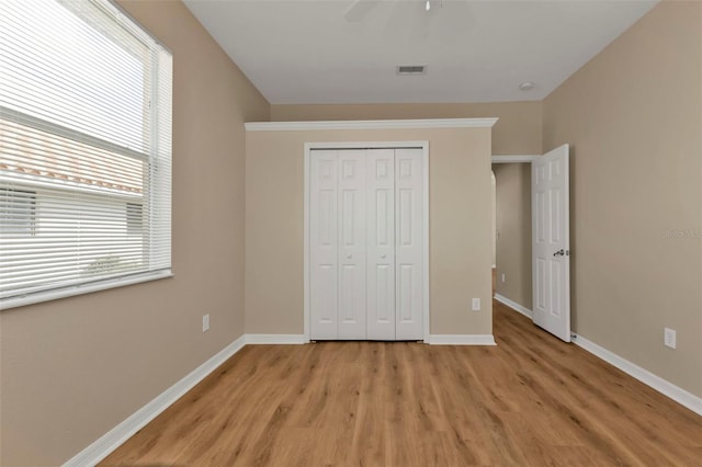 unfurnished bedroom with ceiling fan, light wood-type flooring, and a closet