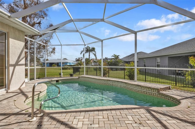 view of pool featuring a lawn, glass enclosure, and a patio area