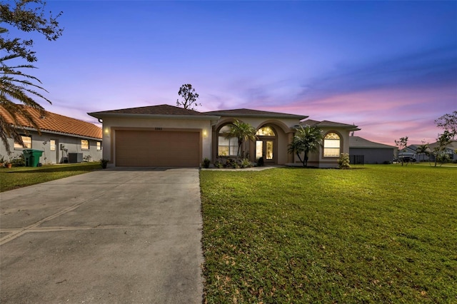 view of front of house featuring a lawn, central AC unit, and a garage