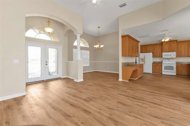 kitchen with light stone counters, ceiling fan with notable chandelier, white appliances, light hardwood / wood-style flooring, and hanging light fixtures