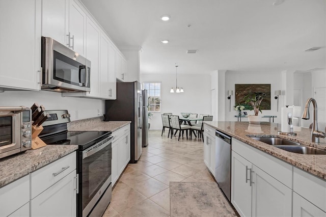 kitchen featuring white cabinetry, appliances with stainless steel finishes, sink, and light stone countertops