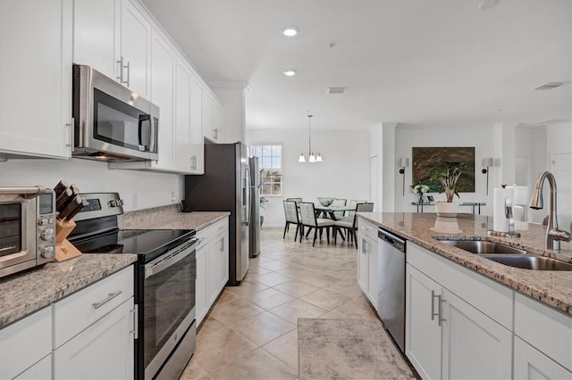 14640 Sycamore Ct Unit 2822, Punta Gorda, FL 33955 - kitchen with stainless steel appliances, a sink, white cabinets, pendant lighting, and light stone countertops