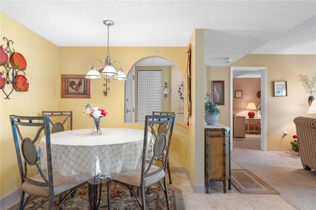 25188 Marion Ave Unit B304, Punta Gorda, FL 33950 - dining space featuring light colored carpet, a textured ceiling, light tile patterned flooring, arched walkways, and baseboards