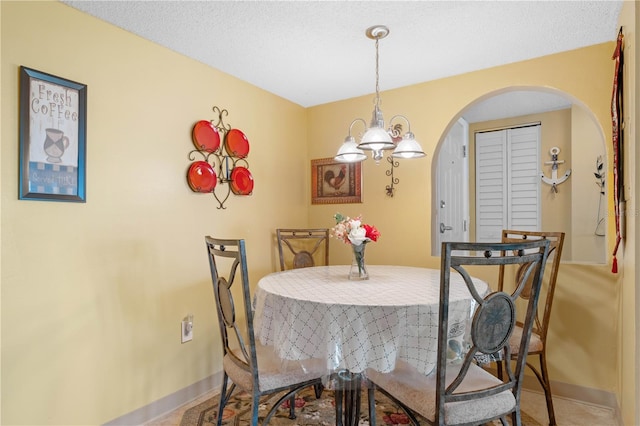 dining room with an inviting chandelier and a textured ceiling