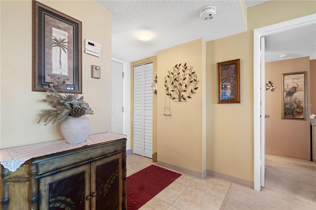 corridor featuring a textured ceiling and light colored carpet