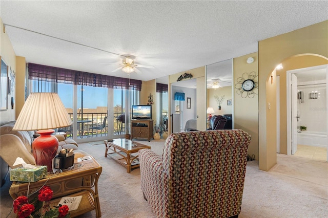 carpeted living room featuring ceiling fan and a textured ceiling