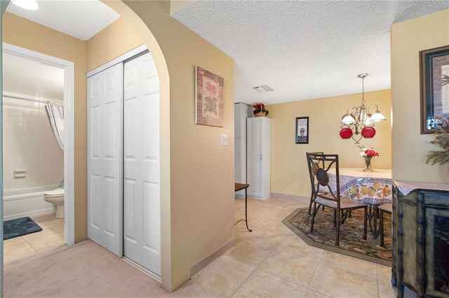 25188 Marion Ave Unit B304, Punta Gorda, FL 33950 - hall featuring light tile patterned floors, a notable chandelier, a textured ceiling, visible vents, and arched walkways