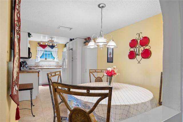 dining area with sink, light tile patterned flooring, a textured ceiling, and an inviting chandelier