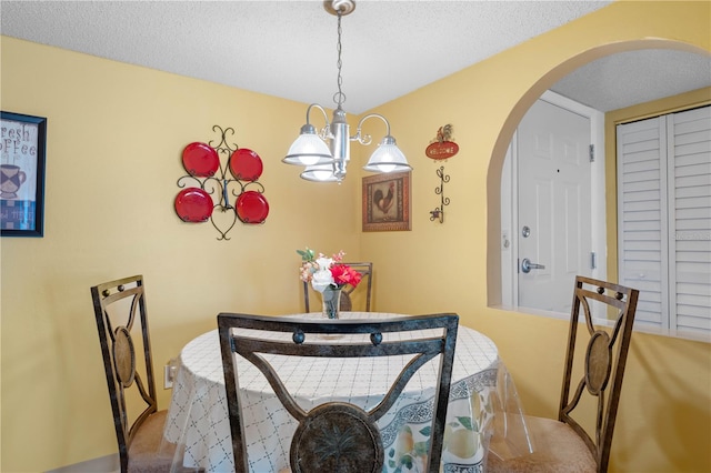 carpeted dining area with a textured ceiling and a chandelier