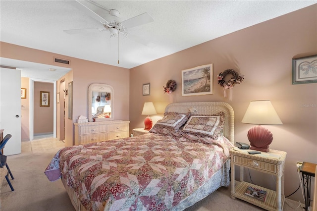 bedroom with ceiling fan, light carpet, and a textured ceiling