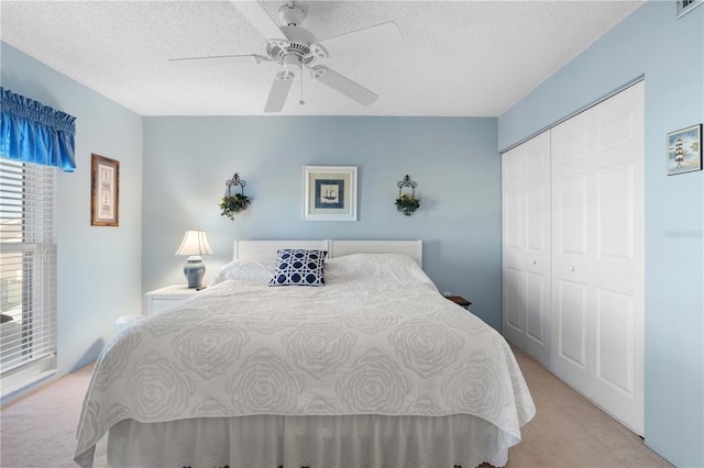 bedroom with a closet, ceiling fan, a textured ceiling, and light colored carpet