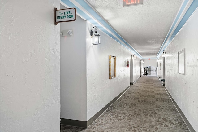 hallway with a textured ceiling and dark carpet