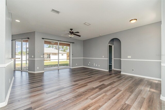 spare room featuring a ceiling fan, baseboards, visible vents, wood finished floors, and arched walkways