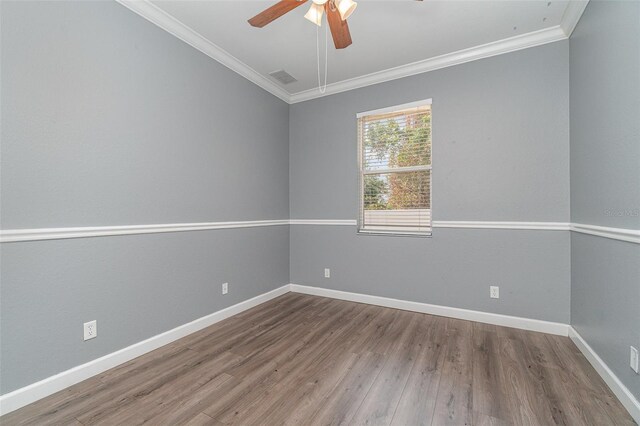 empty room with crown molding, visible vents, wood finished floors, and a ceiling fan