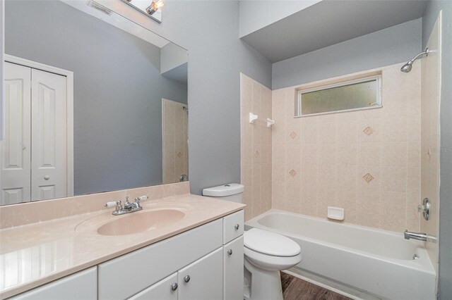 full bath featuring toilet, visible vents, vanity, wood finished floors, and bathing tub / shower combination