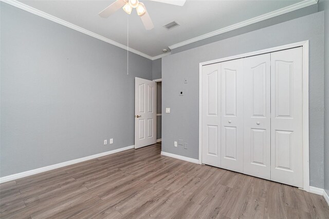 unfurnished bedroom with baseboards, ornamental molding, visible vents, and wood finished floors