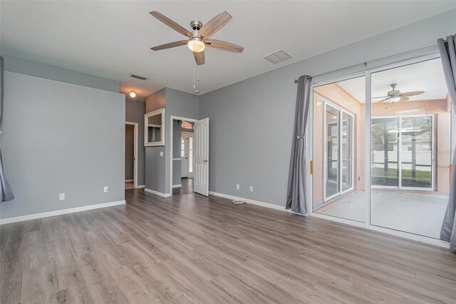 unfurnished room with a ceiling fan, visible vents, and wood finished floors
