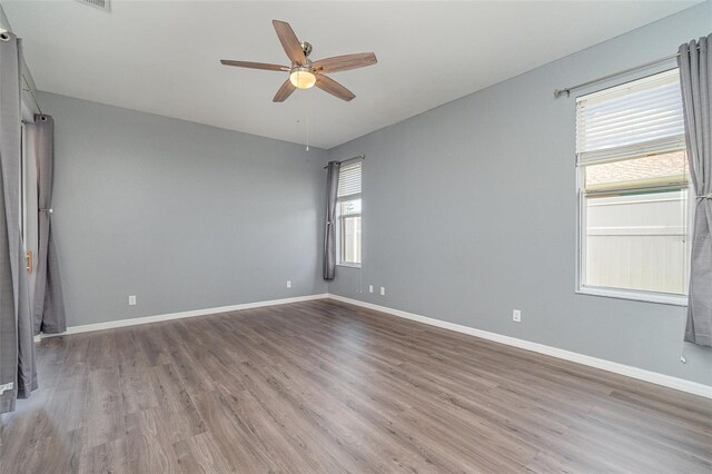 empty room with baseboards, a ceiling fan, and wood finished floors