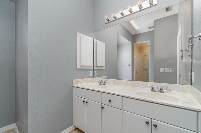bathroom with baseboards, visible vents, a sink, a shower stall, and double vanity