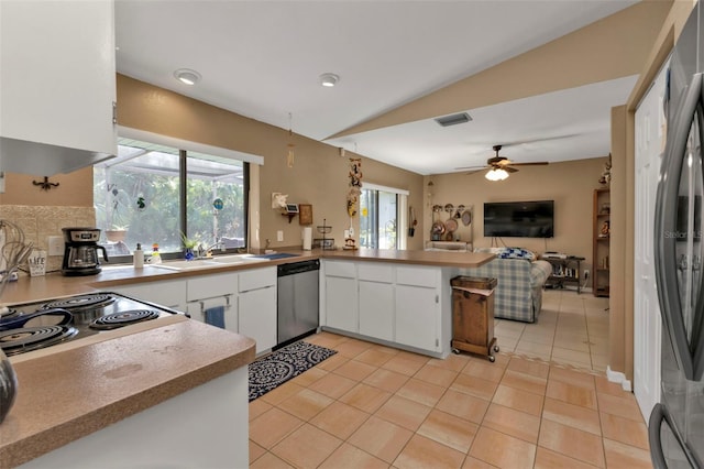 kitchen featuring appliances with stainless steel finishes, kitchen peninsula, white cabinetry, lofted ceiling, and light tile patterned floors