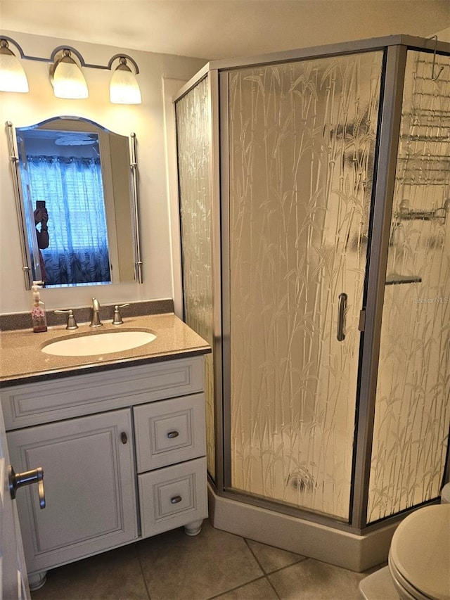 bathroom featuring a shower with shower door, toilet, vanity, and tile patterned flooring