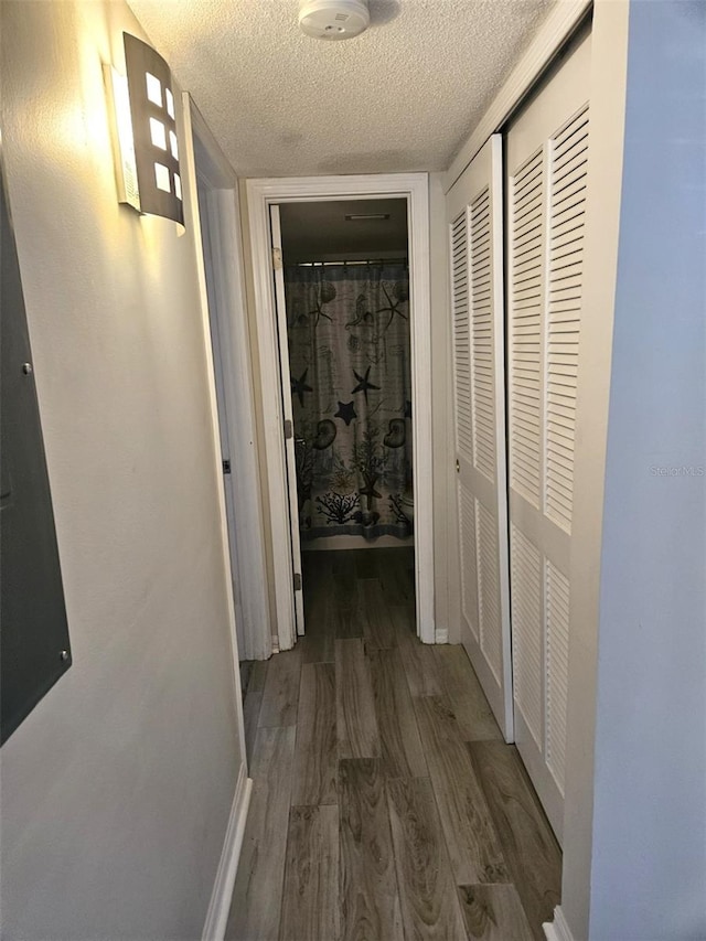 corridor featuring a textured ceiling and hardwood / wood-style flooring