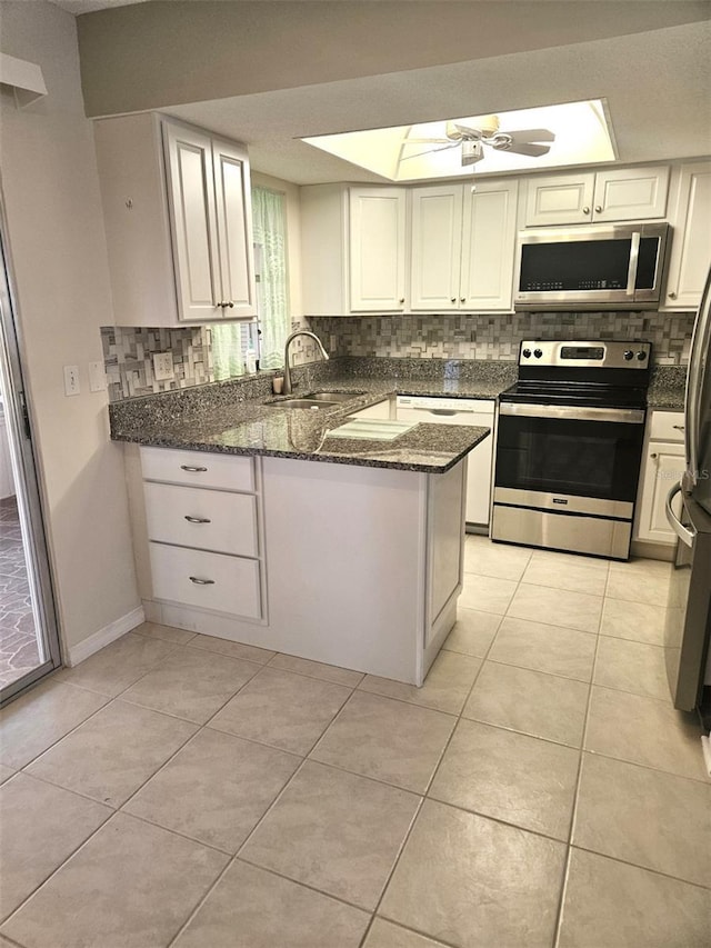 kitchen with light tile patterned flooring, a peninsula, stainless steel appliances, and a sink