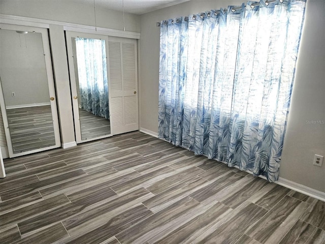 unfurnished room with baseboards and wood finish floors