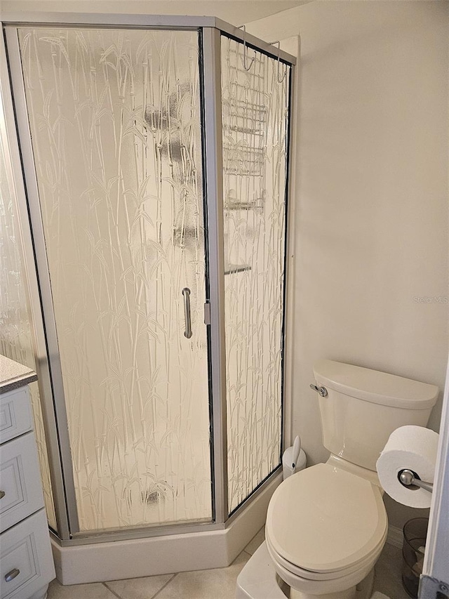 bathroom featuring tile patterned floors, toilet, a stall shower, and vanity